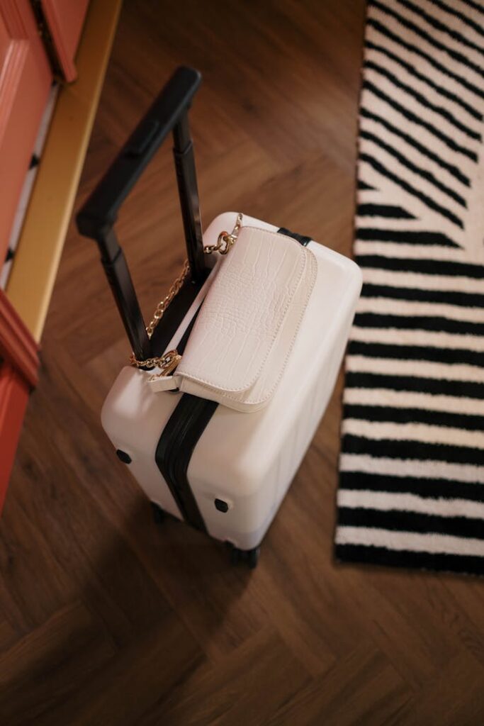 Crafting Captivating Headlines: Your awesome post title goes here Top view of a white suitcase with a stylish handbag on a wooden floor with striped rug.